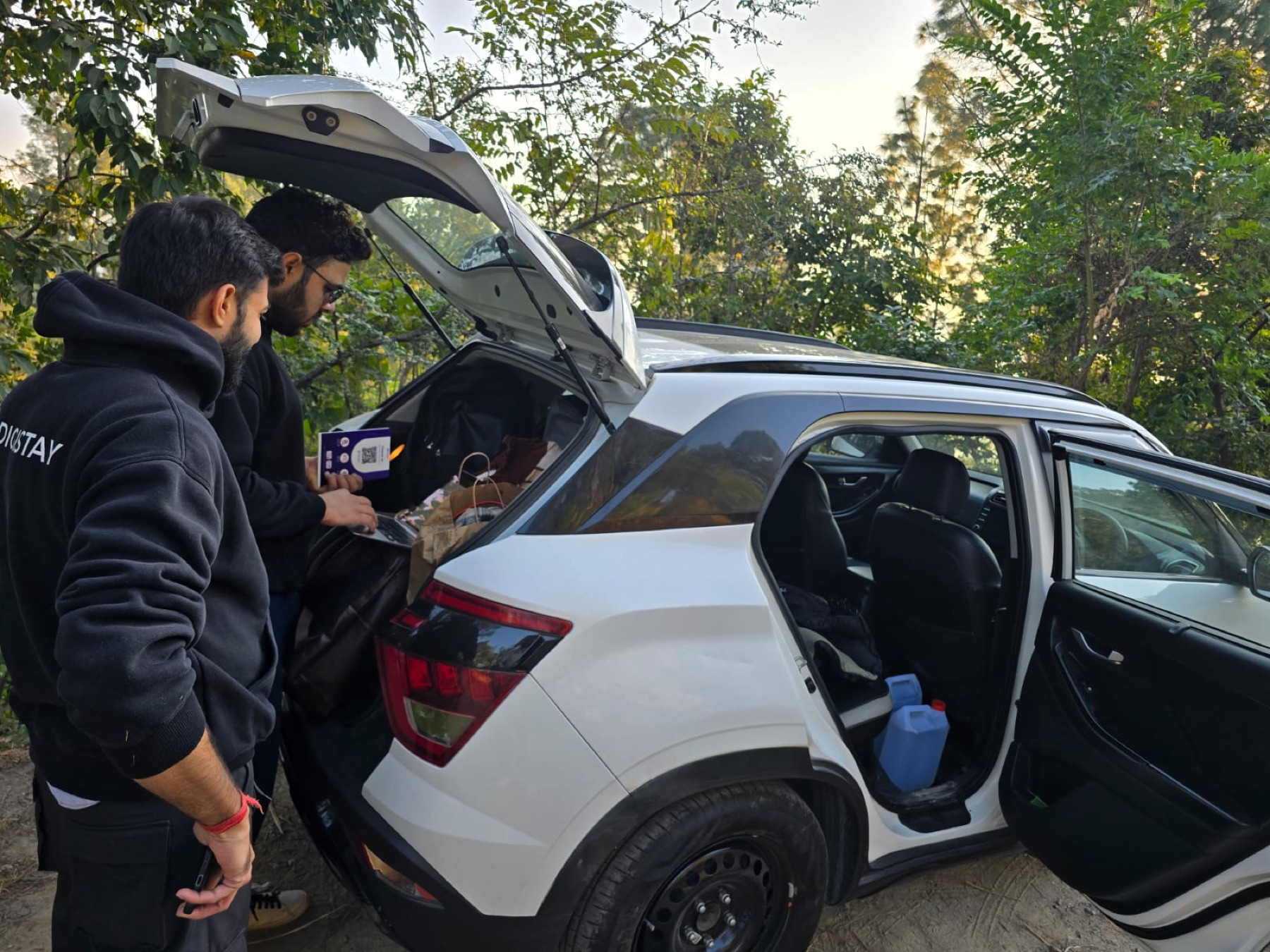 Two DigiStay teammates running the product from a car boot during field onboarding.