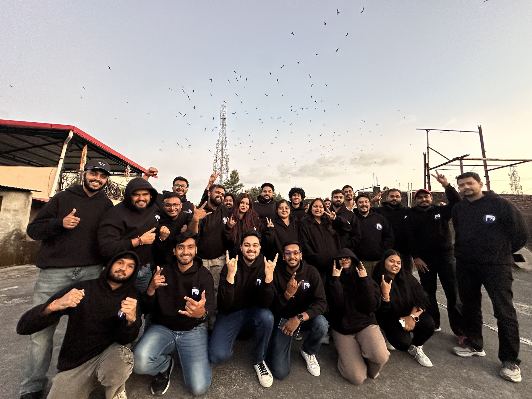 The full DigiStay team in matching hoodies on a rooftop at dusk.